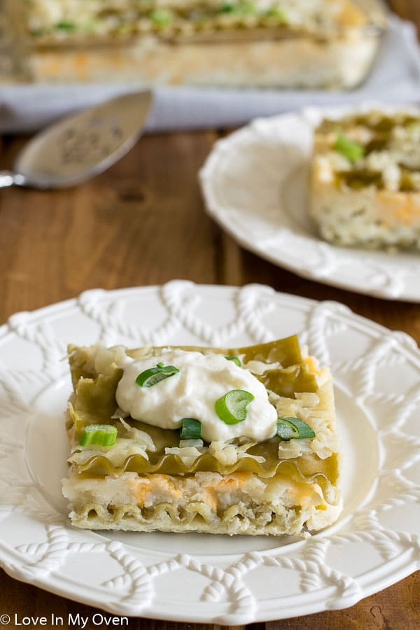 White, green and orange pierogi casserole with ripple edged lasagne noodles and a dollop of sour cream on top sprinkled with chives. 